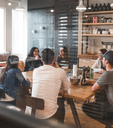 Several people sit round a table in conversation. AML check.