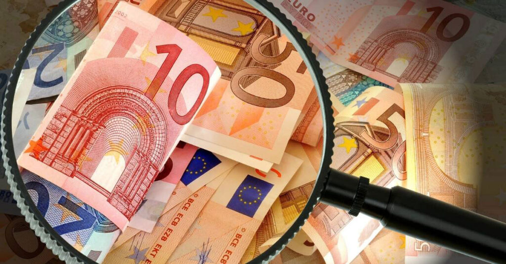 A magnifying glass inspecting a stack of Euros notes. Source of funds.