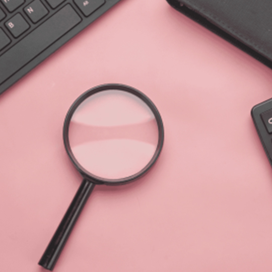 A magnifying glass next to some technology.