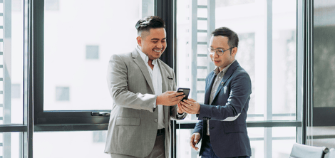 Two people laugh while looking at a phone.