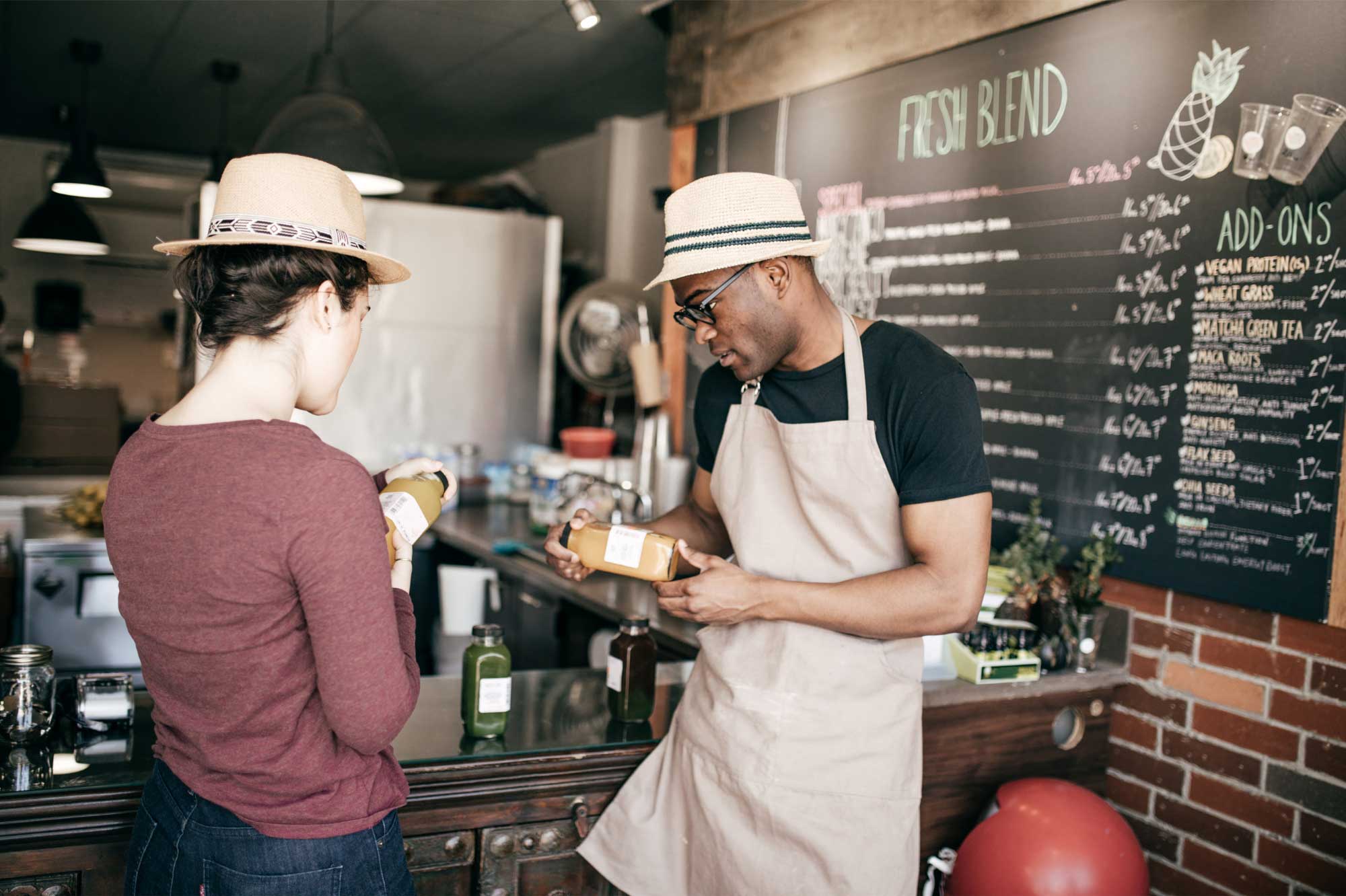 A customer buying fresh juice from a barista in a cool coffee shop.