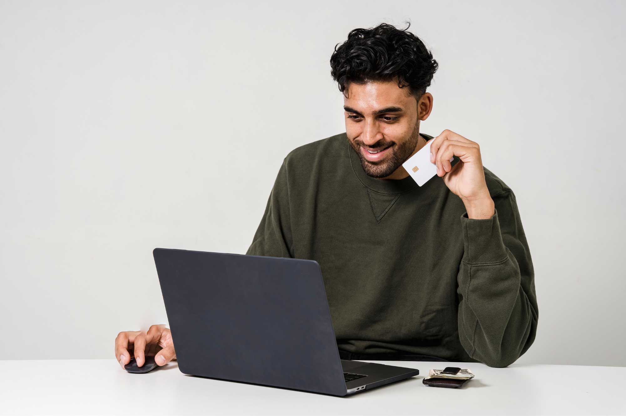 Someone golding a credit card while working on his laptop.