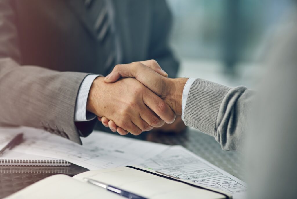 Two businessmen shaking hands over paperwork.