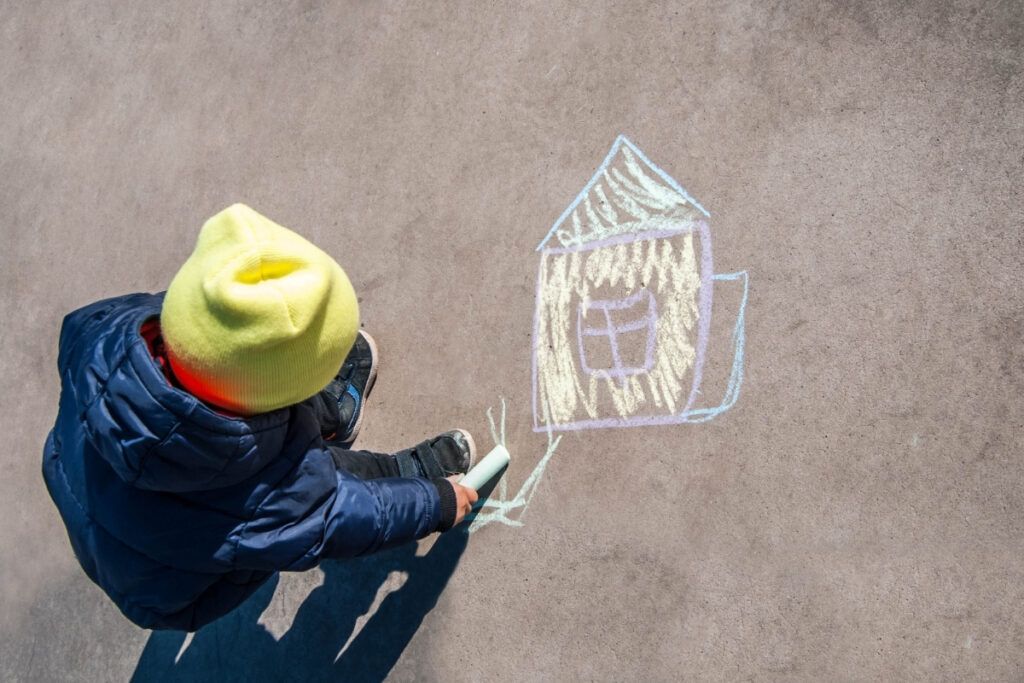 A child draws a chalk picture of a house on the pavement. There are a number of important AML checks when buying a house.
